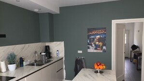 Uma cozinha moderna com bancada de mármore, cafeteira e uma fruteira.