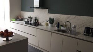 Uma cozinha moderna com bancada de mármore, pia de aço inoxidável e diversos eletrodomésticos e utensílios.