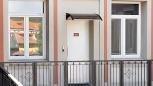 La façana d'un edifici amb tres finestres, una porta i una barana metàl·lica.