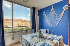 A balcony with a table, chairs, a hammock, and a view of buildings. - “L’Escale Marine” – AC, Beach, Sleeps 4 (Sète)