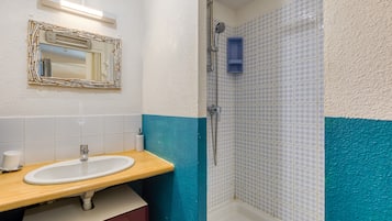 A bathroom with a sink, mirror, and shower.
