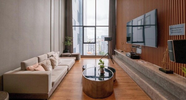 Ein modernes Wohnzimmer mit einer Couch, einem Couchtisch, einem Fernseher und Blick auf die Stadt.