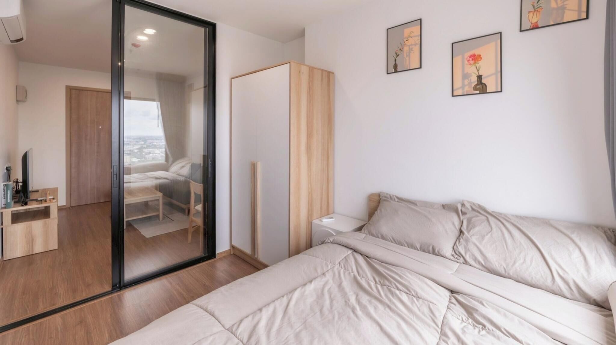A bedroom with a bed, a wardrobe, a nightstand, and a view through a glass door.