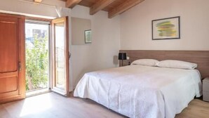 A bedroom with a wooden ceiling, a bed with white bedding, a nightstand, and a window. - Don Giovanni (Acireale)