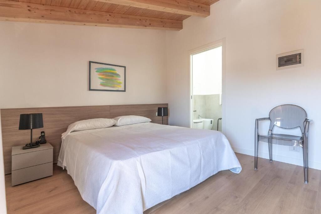 A bedroom with a bed, bedside tables, a chair, and a window.