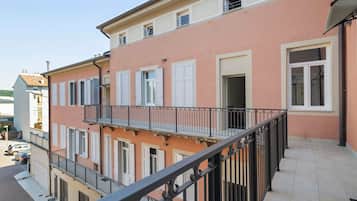 Un immeuble à plusieurs étages doté de balcons, avec un rez-de-chaussée carrelé et un ciel dégagé.