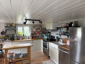 Cucina con mobili in legno, frigorifero in acciaio inossidabile e diversi elettrodomestici.