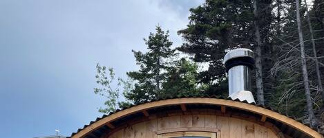 Une cabane en bois avec une grande fenêtre, une porte et une cheminée.