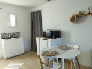 A compact kitchen with a microwave, coffee maker, and a small refrigerator. There is a dining table with two chairs and a woven placemat. - The Castle (Sommières)