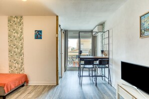 Ein Zimmer mit Bett, Schreibtisch mit Stühlen, Fernseher und Balkon mit Blick.