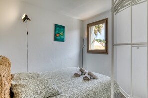 Ein Schlafzimmer mit einem Bett, einem Gemälde, einem Fenster mit Blick und einer Stehlampe.