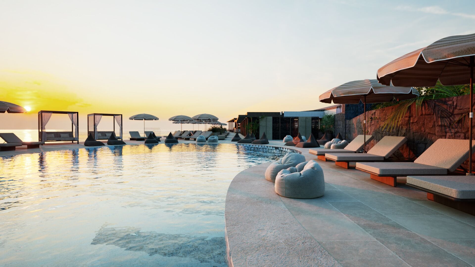 Zona junto a la piscina con sillones de descanso y sombrillas, cielo despejado y atardecer.