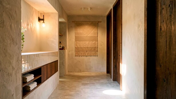 Um corredor com uma porta de madeira, um porta-toalhas na parede e um tecido trançado pendurado.