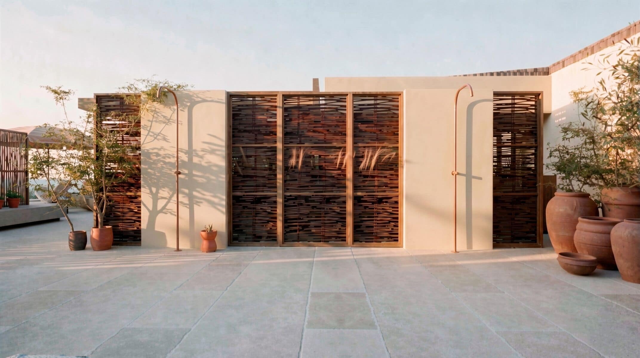 Un edificio moderno con techo plano, ventanas amplias y varias macetas con plantas.