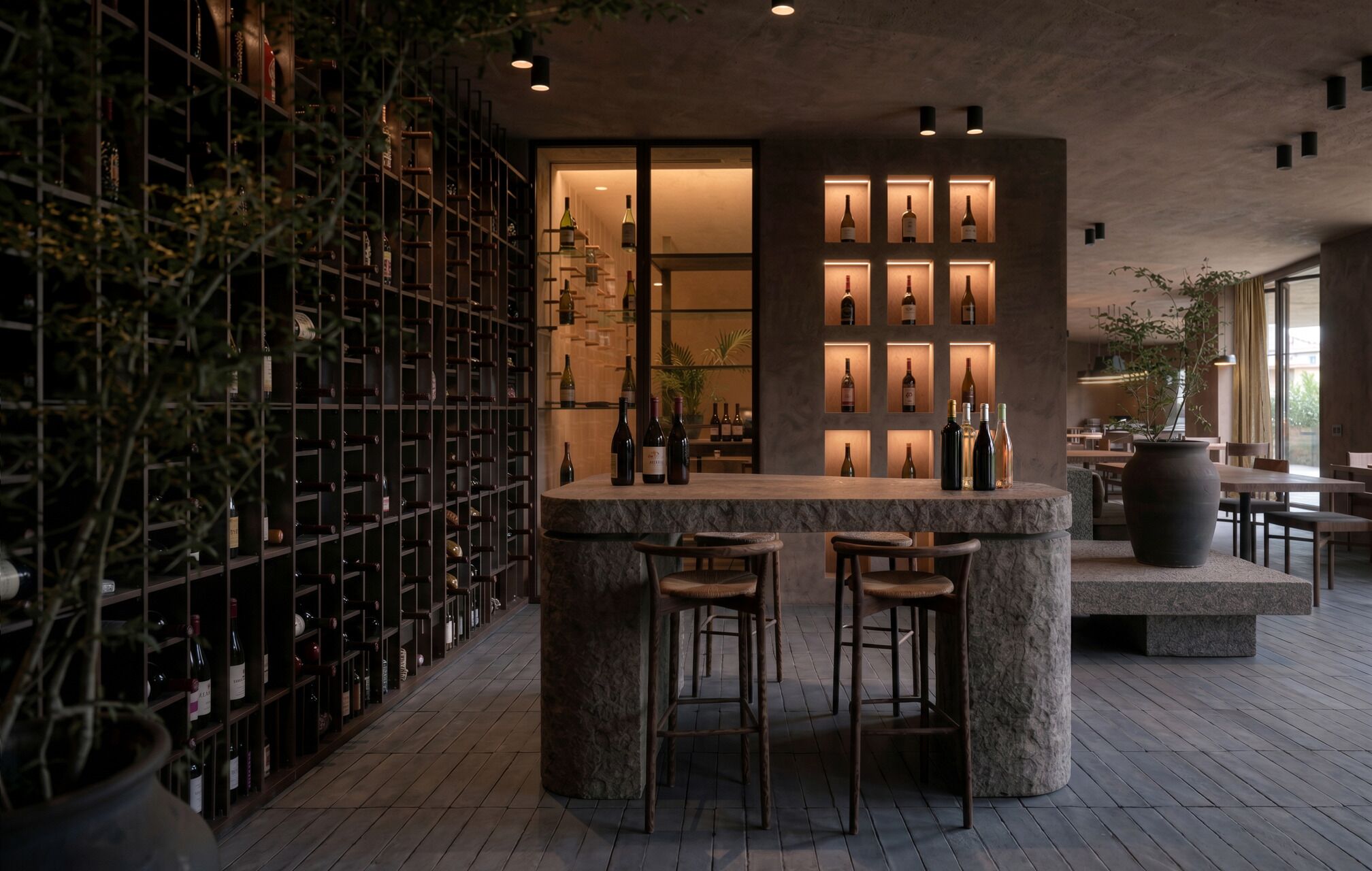 Una zona de bar con una bodega, taburetes y un área de estar con mesas y sillas.
