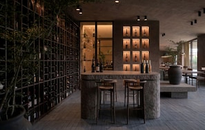 A bar area with a wine rack, stools, and a seating area with tables and chairs. - Ella Elyra - Adults Only - All Inclusive (Corfu)