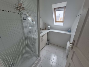 Ein Badezimmer mit Dusche, kleinem Fenster und Toilette.