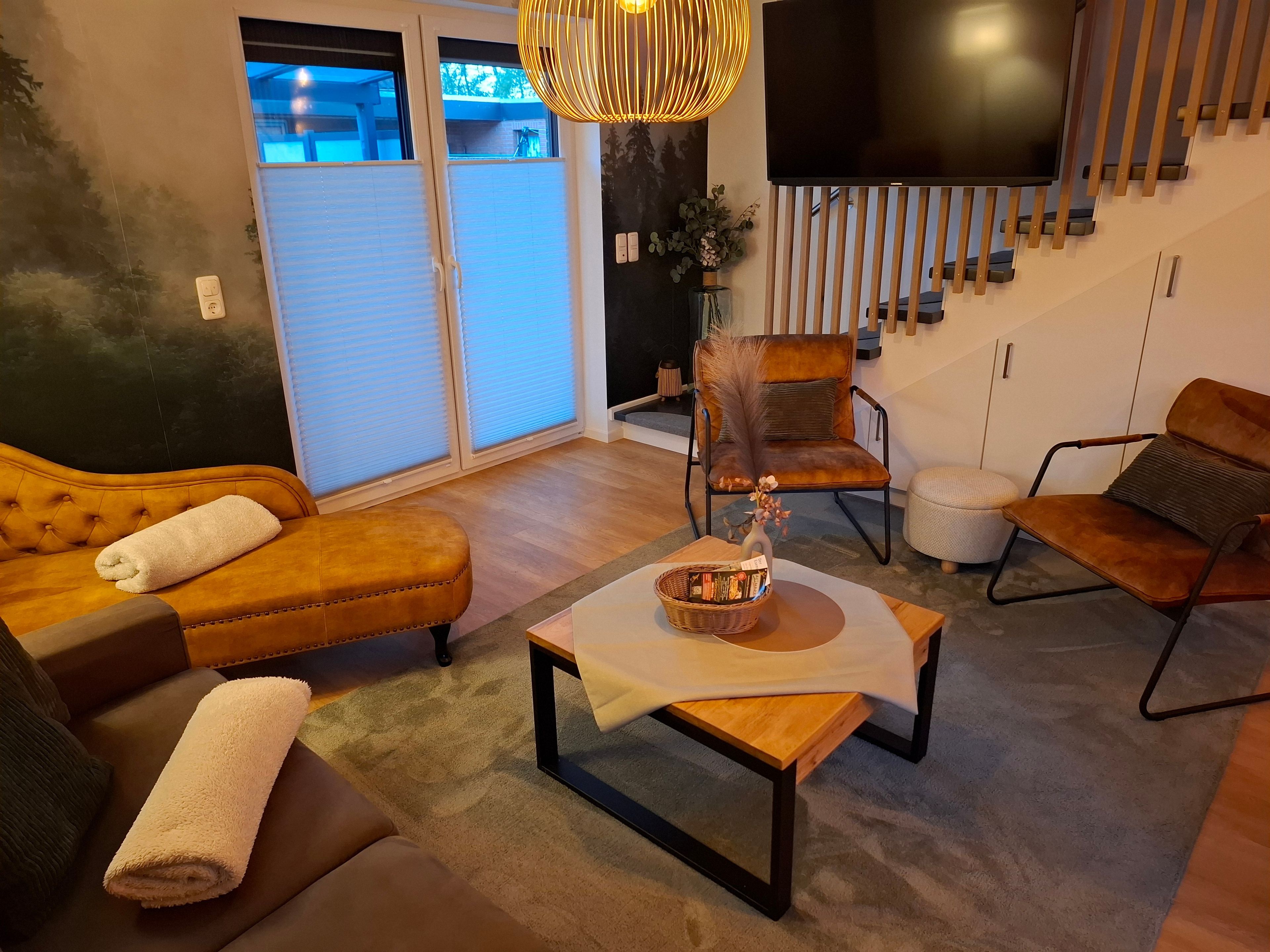 A living room with a sofa, armchair, ottoman, and a coffee table with a vase.