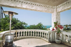 Ein überdachter Außenbereich mit Steinbalustrade, einem Heizstrahler und Topfpflanzen.