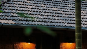 A brick building with a tiled roof, a wooden door, and a small porch with steps. - Arika Goa (Neturlim)