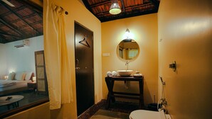 A bathroom with a toilet, sink, and mirror. - Arika Goa (Neturlim)