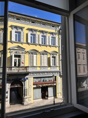 Ein gelbes Gebäude mit einem Balkon, ein Geschäft mit einer roten Markise und eine Flagge.