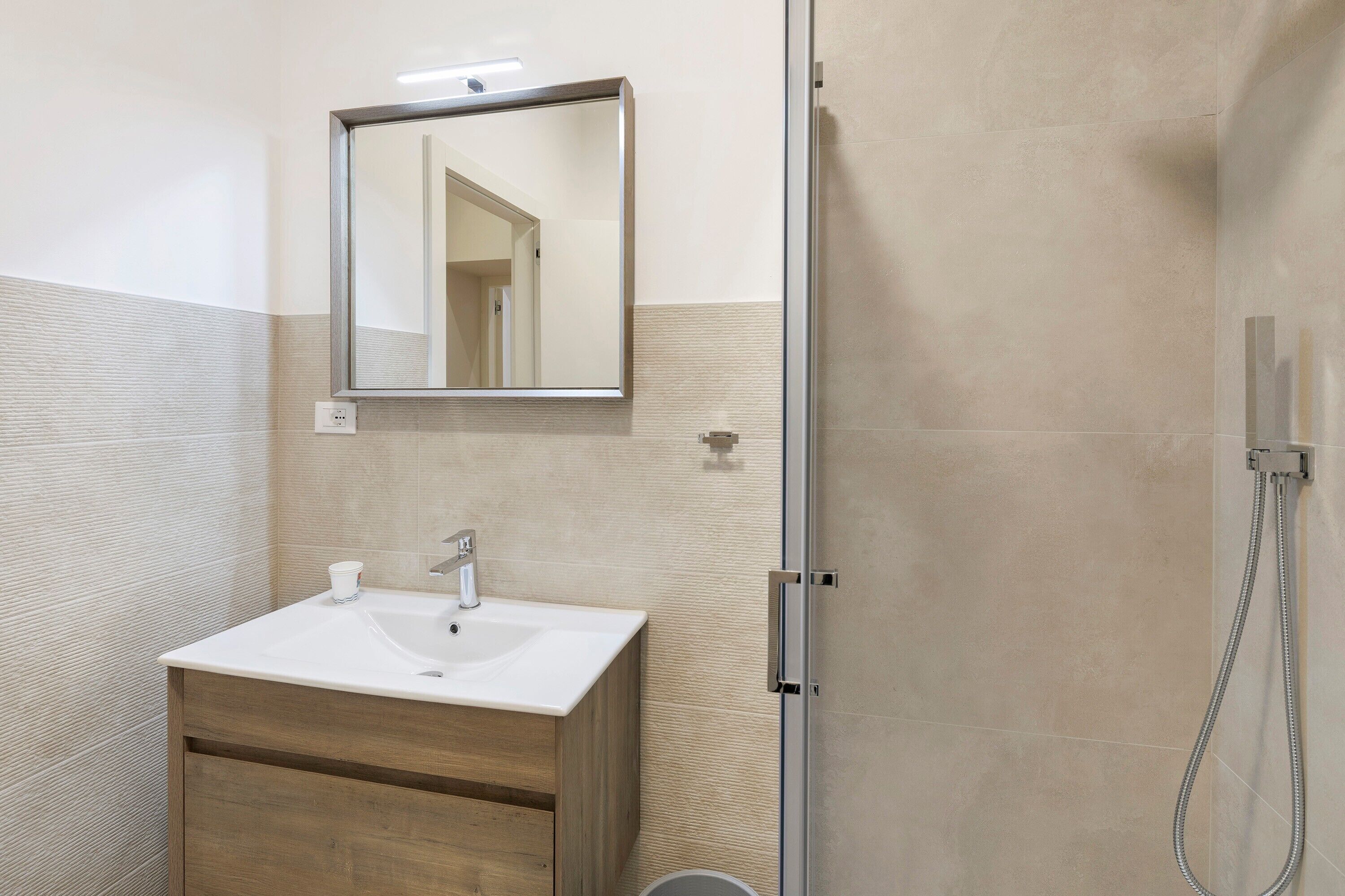 Une salle de bain avec un lavabo blanc, un miroir et une douche.