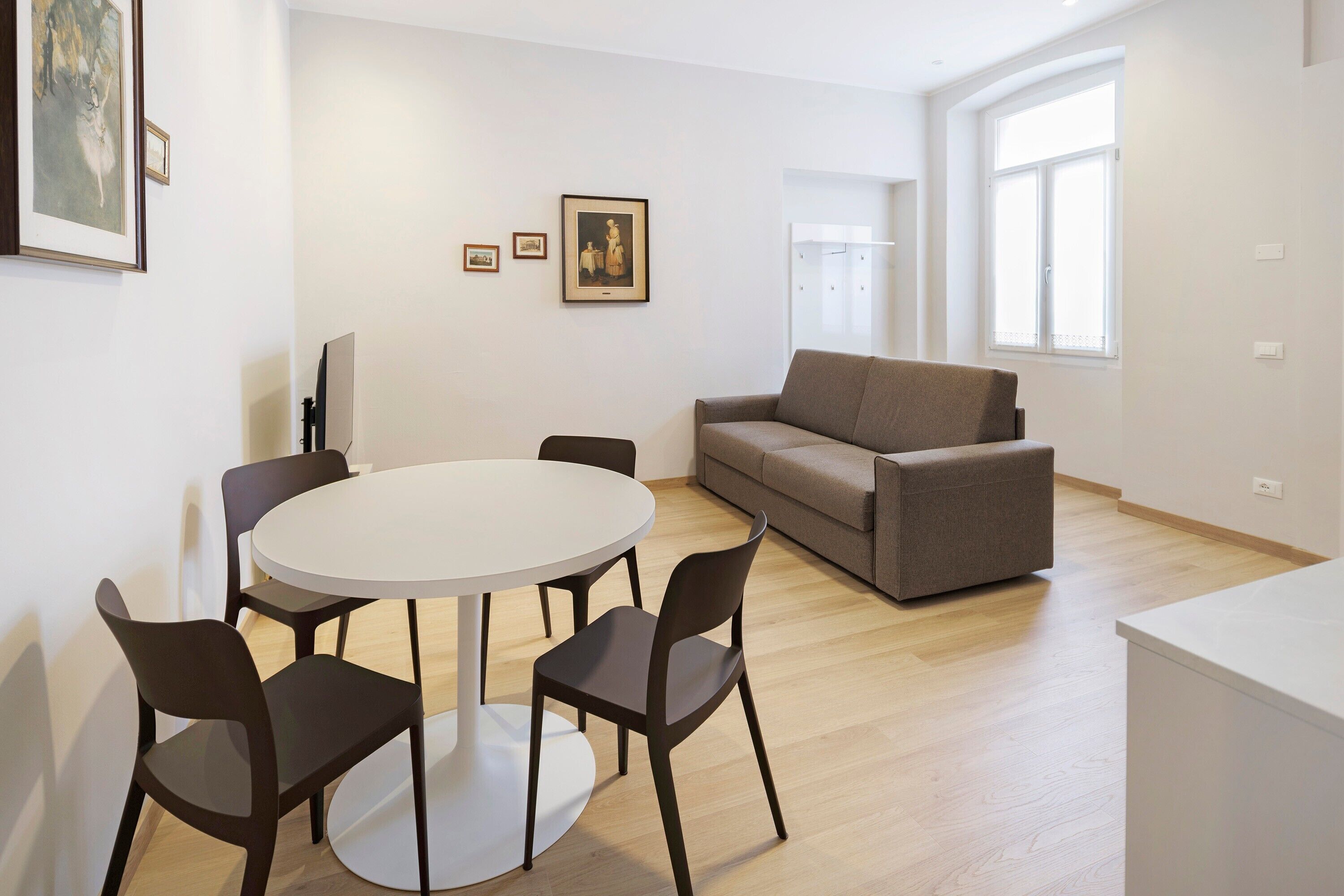 Un salon moderne avec une table ronde, quatre chaises, un canapé et un téléviseur.