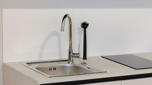 Eine moderne Küche mit einer Spüle aus Edelstahl, einem Wasserhahn und einer schwarzen Bürste.