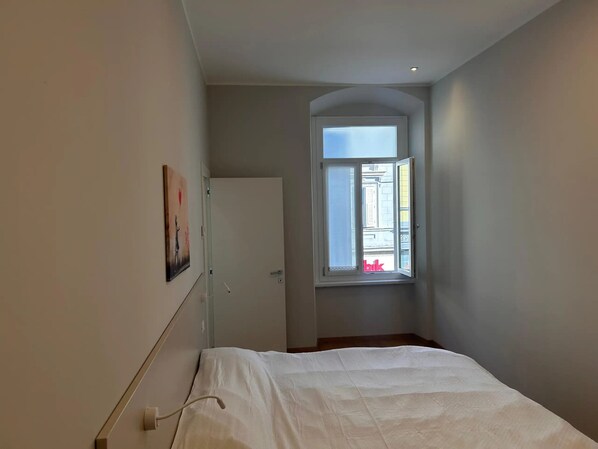 A bedroom with a single bed, a window with a view of the street, and a door leading to another room. - Apartment 'Verdi' in Gorizia (Gorizia)