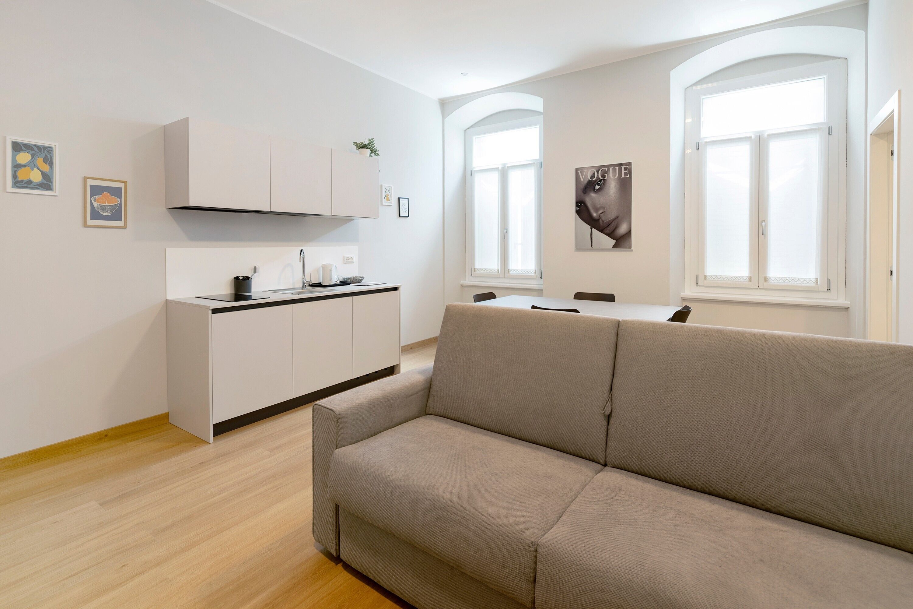 Un espacio moderno para vivir con sofá, kitchenette y ventanas amplias.