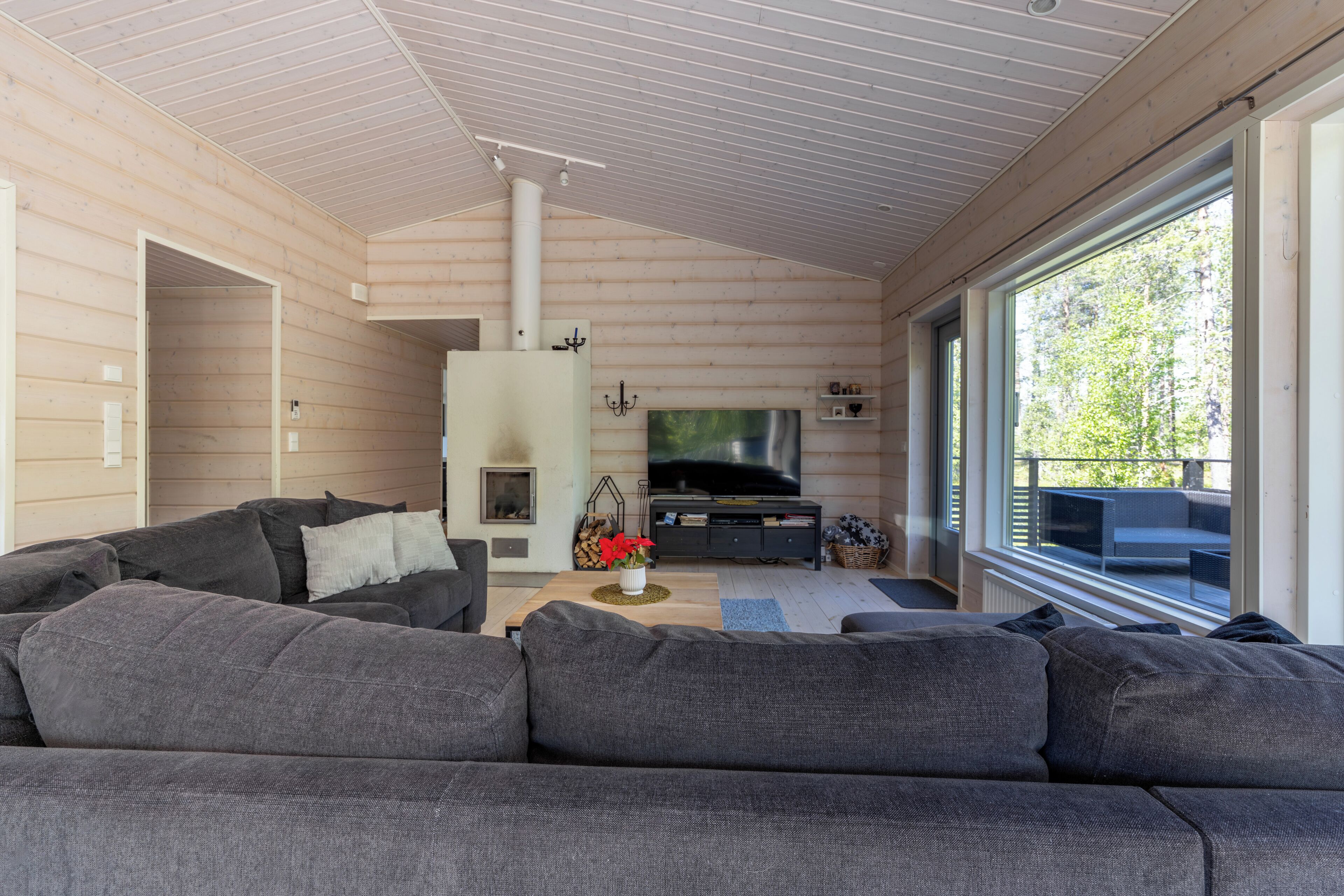 Una sala de estar moderna con un sofá grande color gris, una chimenea, un televisor de pantalla plana y ventanas amplias.