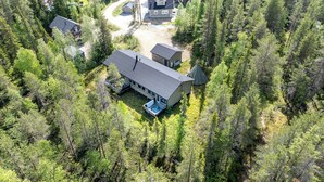 Vue aérienne d’un chalet doté d’un bain à remous, entouré d’une forêt dense.