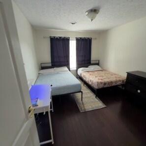 Een slaapkamer met twee bedden, een bureau en een kledingkast.