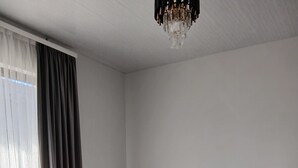 Un dormitorio con cama, mesita de noche, candelabro y ventana con cortinas.