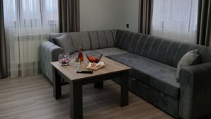 Una sala de estar moderna con un sofá seccional gris, una mesa de centro de madera y una araña.