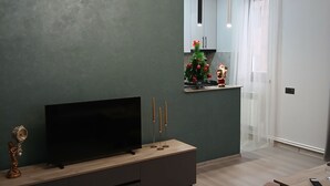 Una sala de estar moderna con un televisor de pantalla plana, un mueble de entretenimiento de madera, una araña y un árbol de Navidad.