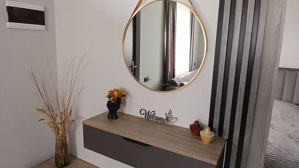 Un baño moderno con tocador, espejo, banco y un jarrón decorativo.