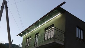 Un edificio con balcón, pared de piedra y garaje.