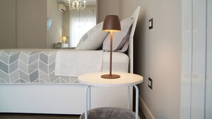 Una camera da letto ordinata con un letto, un comodino con una lampada, uno specchio e un lampadario.