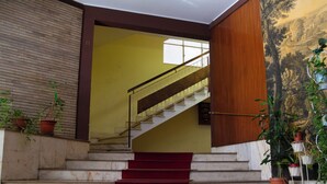 Una scala con tappeto rosso che conduce a una stanza con una parete gialla e pannelli in legno.