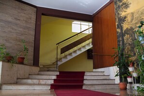Eine Treppe mit rotem Teppich führt zu einem Raum, der eine gelbe Wand und ein Holzpaneel hat.
