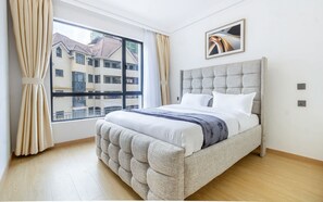 Un dormitorio moderno con una cama grande, una ventana con cortinas y vistas a edificios.