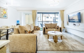 A modern living room with a sofa set, a coffee table, and a TV mounted on the wall. - Riara - The Urban Haven (Nairobi)