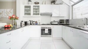 A modern kitchen with white cabinets, a built-in oven, a microwave, and a toaster. - Villa Atlantica  (Cape Town)