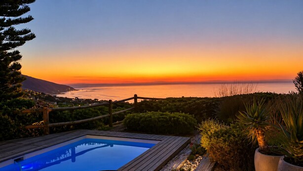 A pool with a wooden deck, a fire pit, and a view of the ocean at sunset. - Villa Atlantica  (Cape Town)