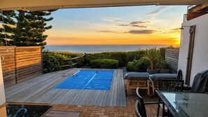 A rooftop patio with a pool, outdoor furniture, and a view of the ocean at sunset. - Villa Atlantica  (Cape Town)