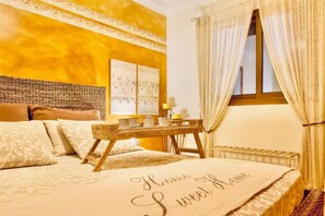 Een slaapkamer met een bed, een nachtkastje, een raam met gordijnen en een muur met een reliëfpatroon.