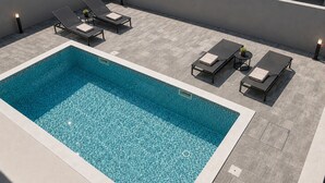 A rooftop pool area with a rectangular pool, lounge chairs, and tables. - Amazing home in Privlaka (Privlaka)