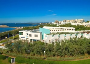 Ein Küstenhotel mit moderner Architektur, einem Poolbereich und Blick auf das Meer.